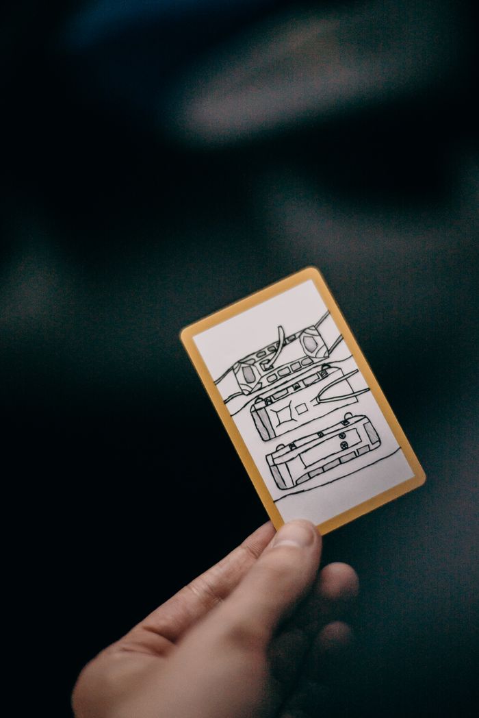 Crafting Captivating Headlines: Your awesome post title goes here Close-up shot of a hand holding an illustrated card featuring travel-themed sketches.
